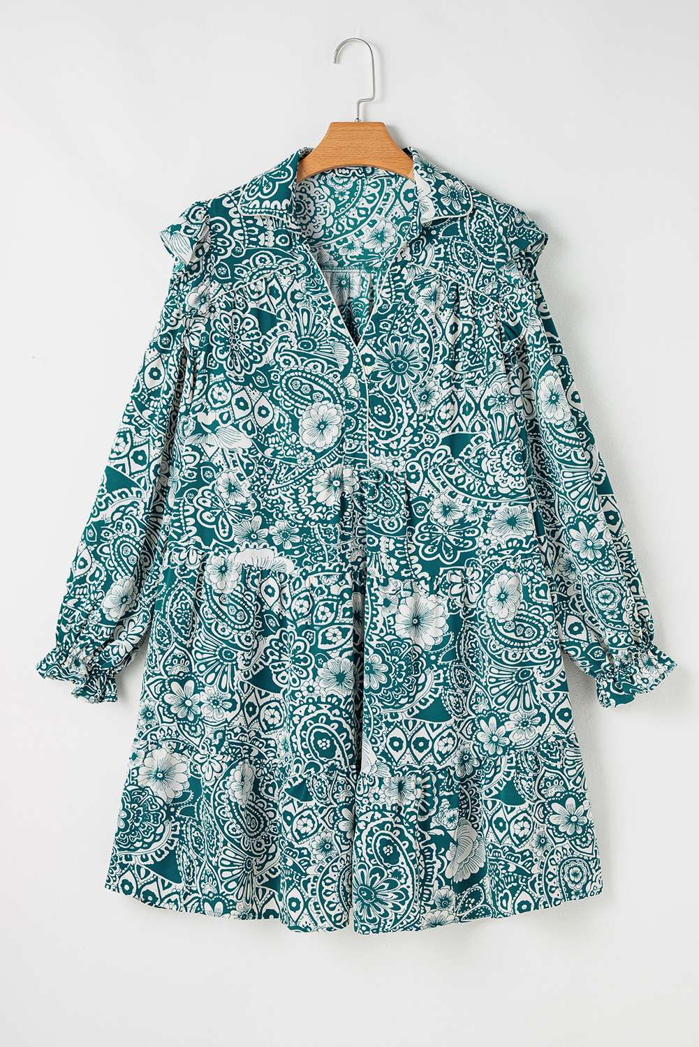 Robe turquoise à imprimé floral, col V avec boutons, dos et manches longues sur cintre.