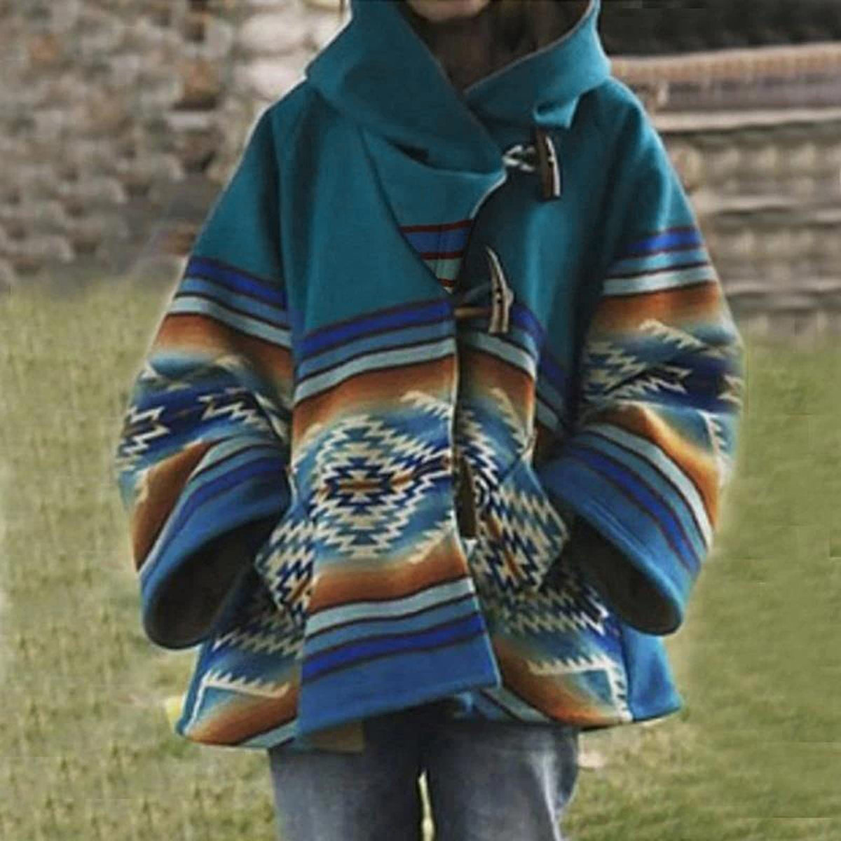 Détail du manteau à capuche femme turquoise, bande ethnique bleue et orange, mains dans les poches