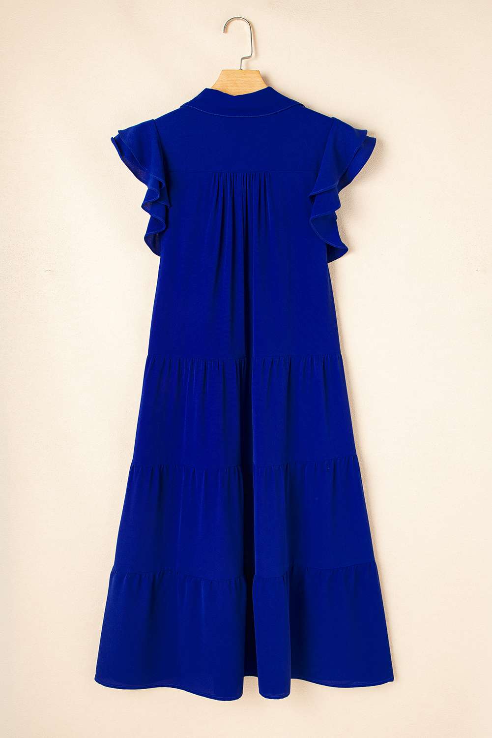 Robe midi bleue sur cintre, dos avec coutures, manches volantées et volants superposés.