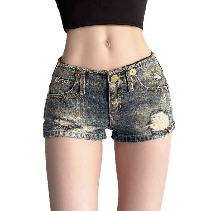 Short en denim bleu vintage pour femme, boutons dorés, ourlet effiloché, déchirures.