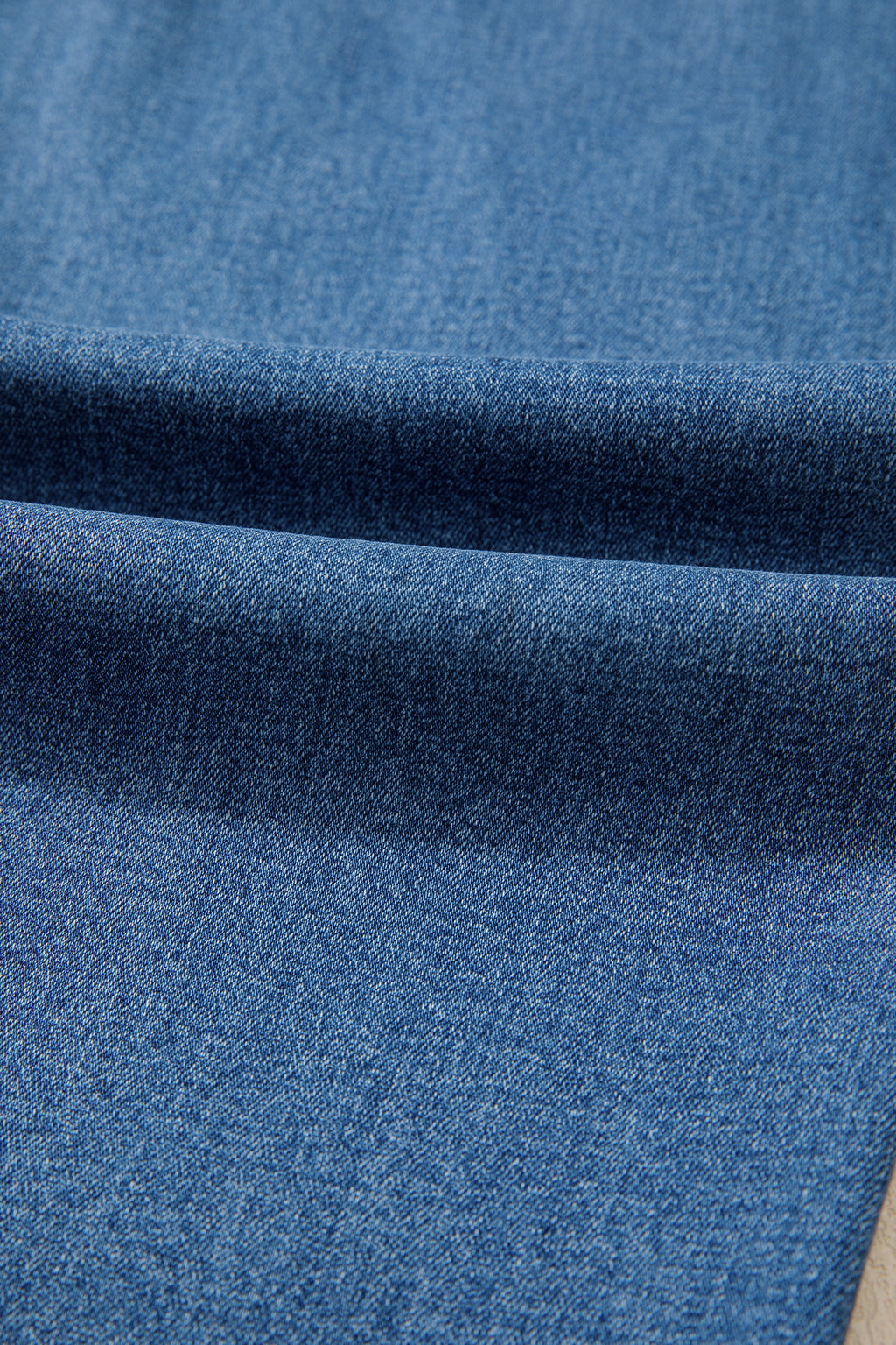Tissu jean bleu myosotis, délavage dégradé sur la jambe droite.