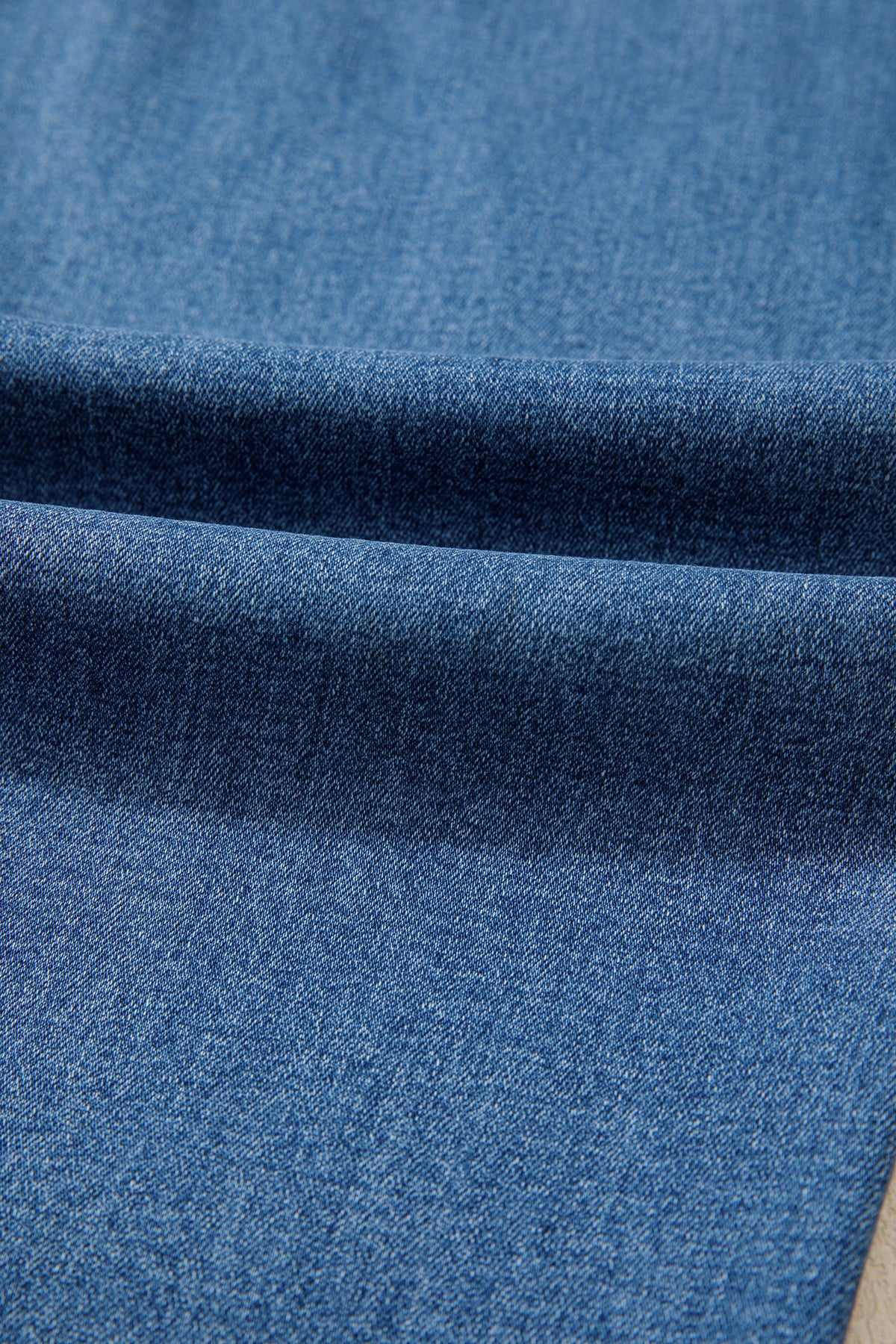 Tissu jean bleu myosotis, délavage dégradé sur la jambe droite.