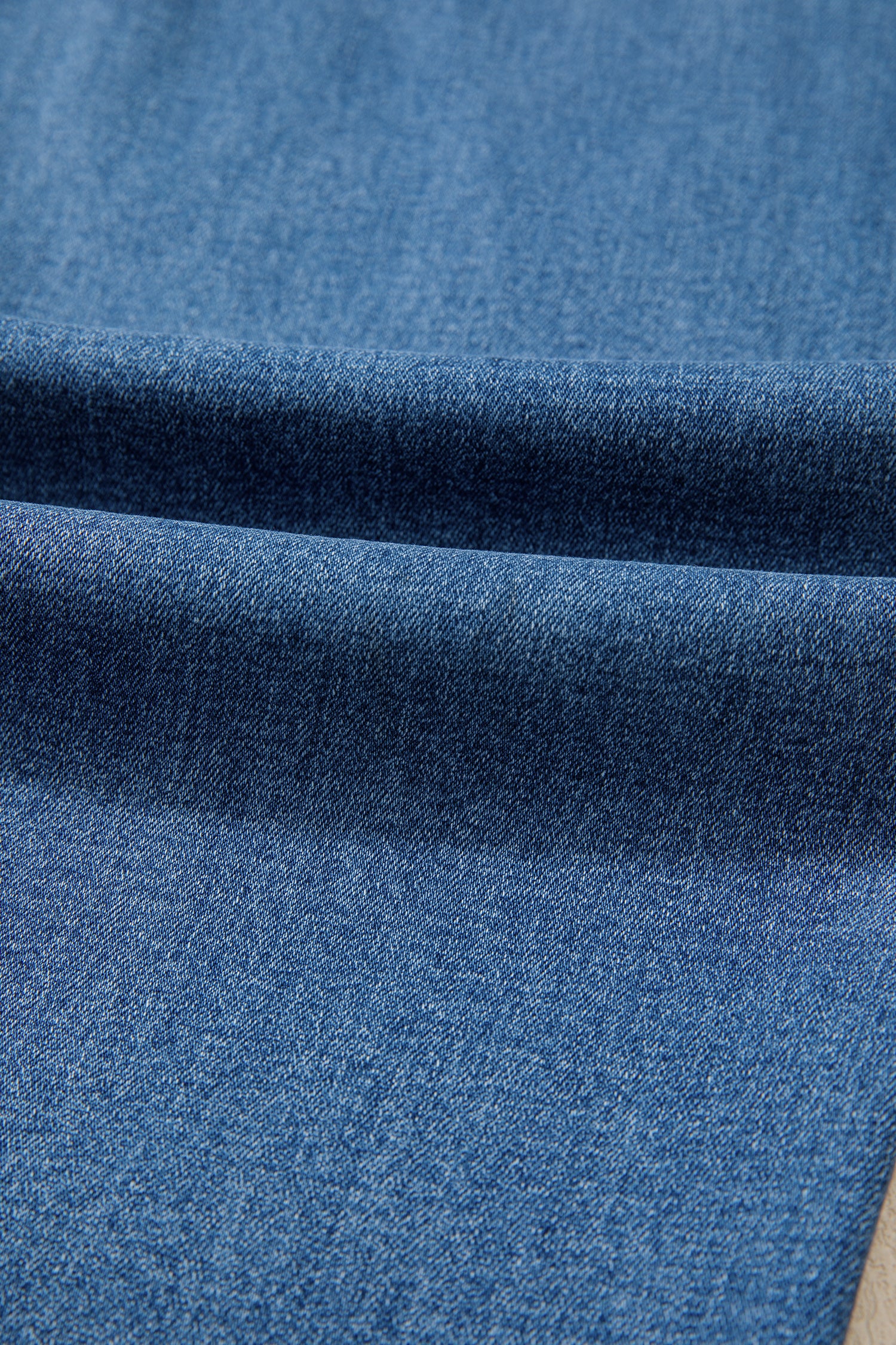 Tissu jean bleu myosotis, délavage dégradé sur la jambe droite.