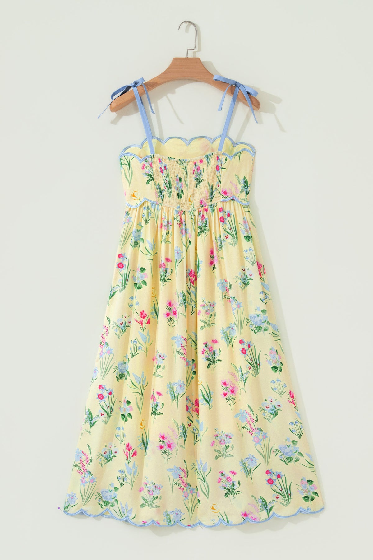 Robe midi à bretelles crème, fleurs multicolores, taille haute froncée, bord bleu.