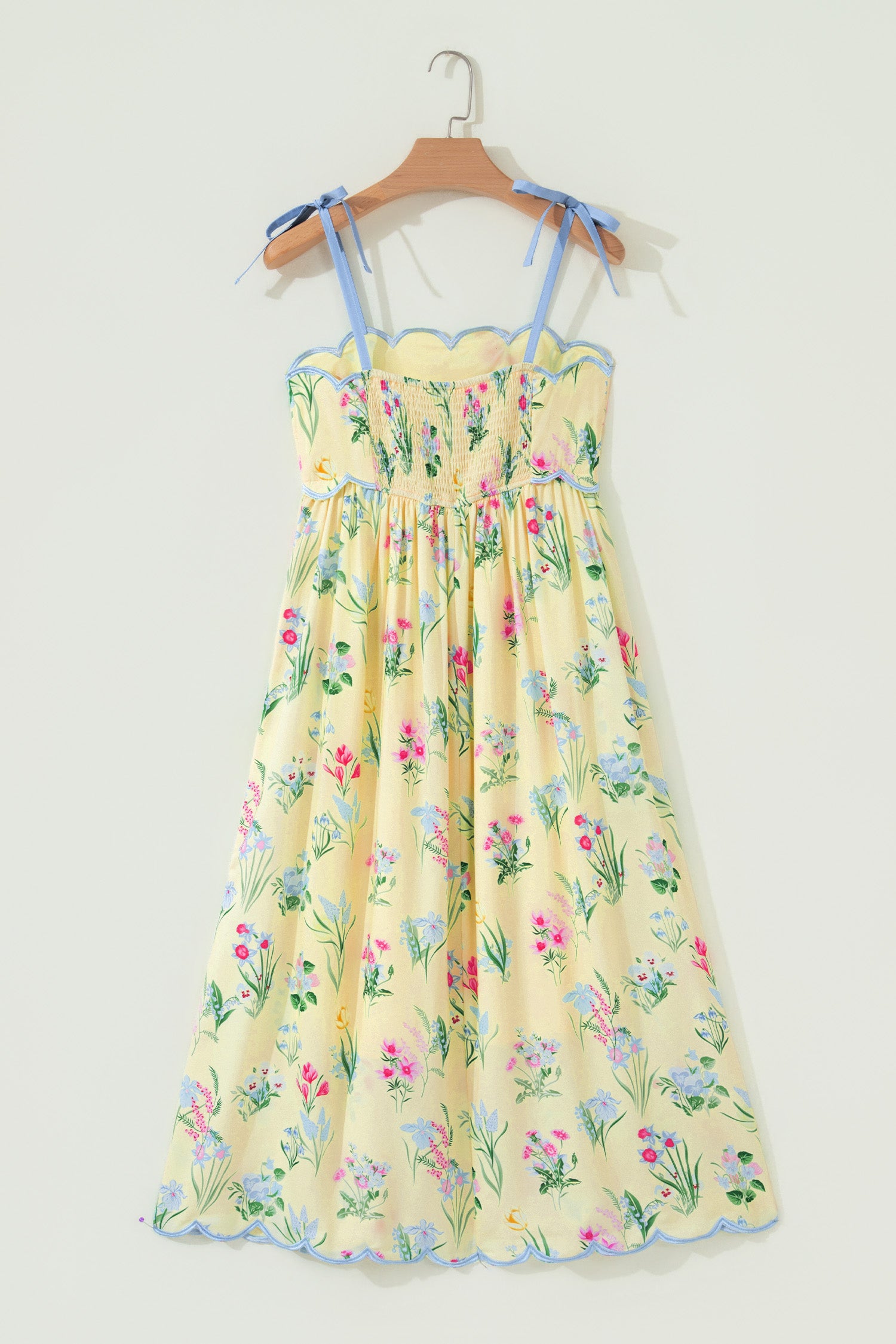 Robe midi à bretelles crème, fleurs multicolores, taille haute froncée, bord bleu.