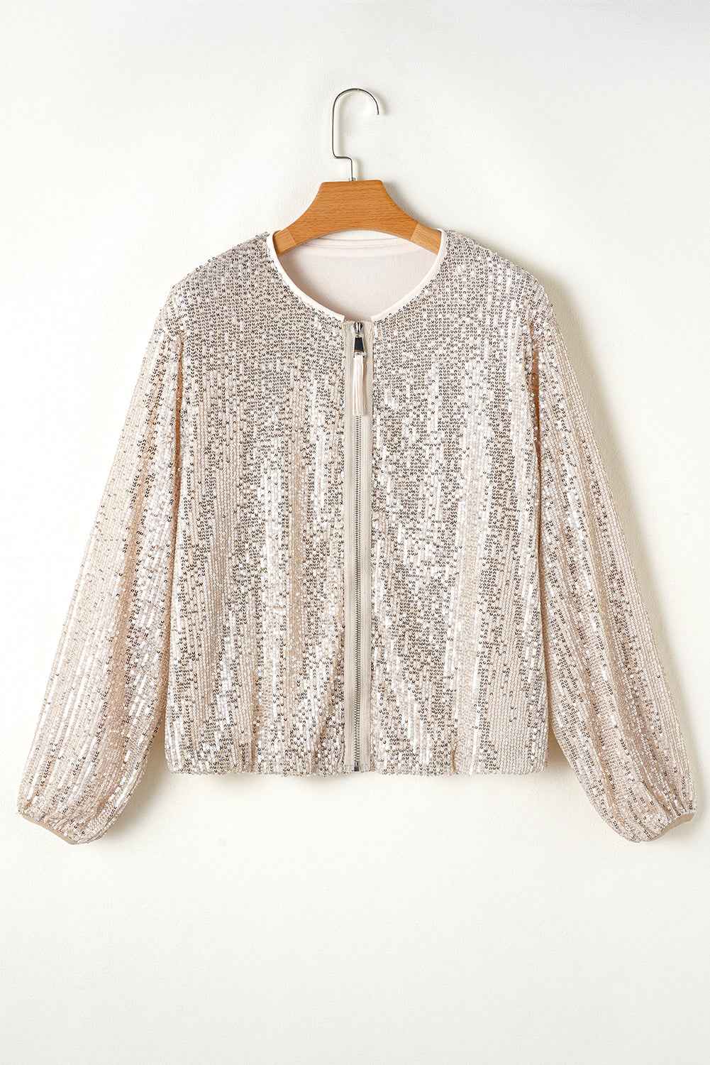Veste à sequins argentée sur cintre, manches longues, col rond, fermeture centrale.
