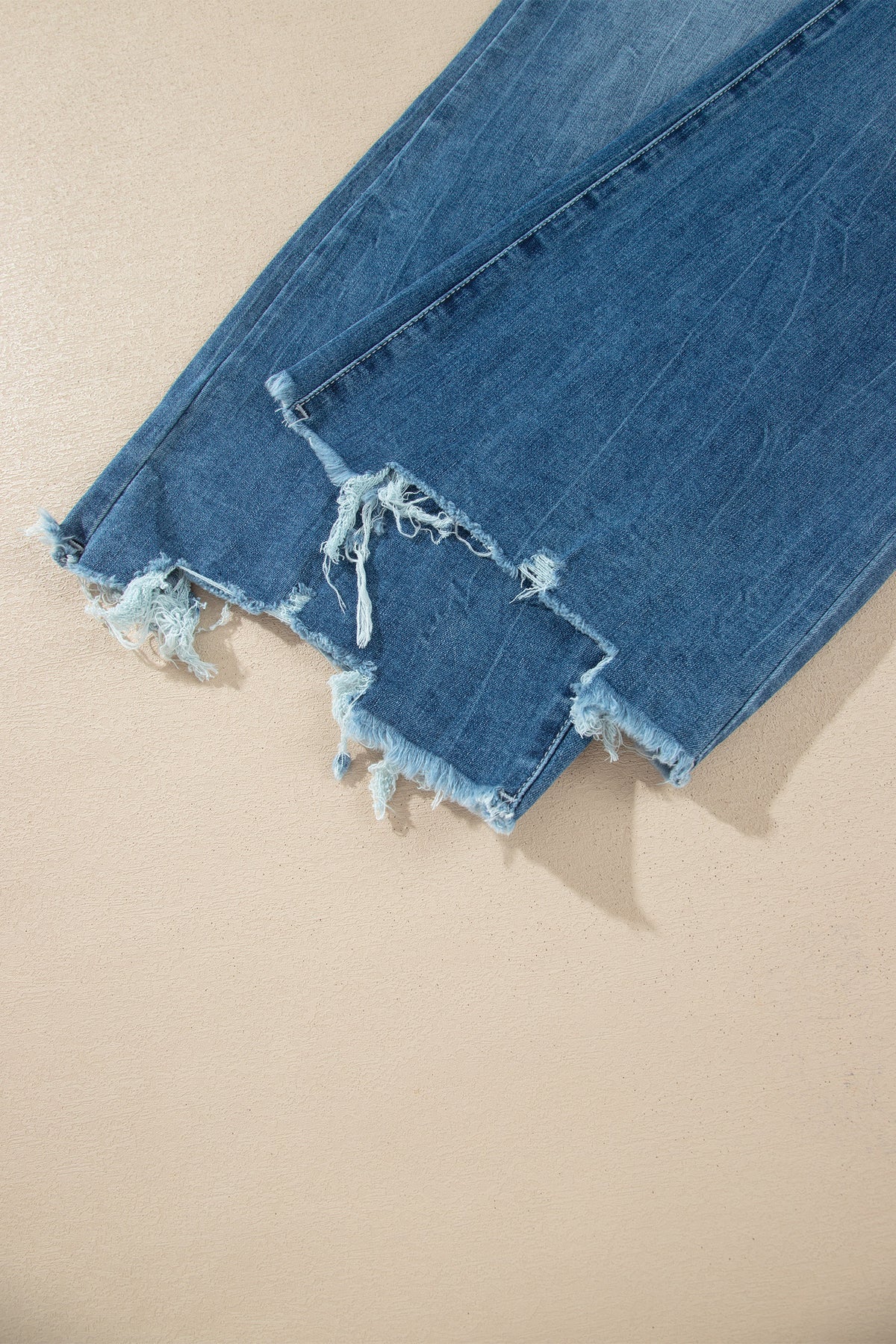 Jean flare taille haute bleu moyen, ourlet effiloché avec filaments et dégradé d’usure.