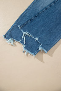 Jean flare taille haute bleu moyen, ourlet effiloché avec filaments et dégradé d’usure.