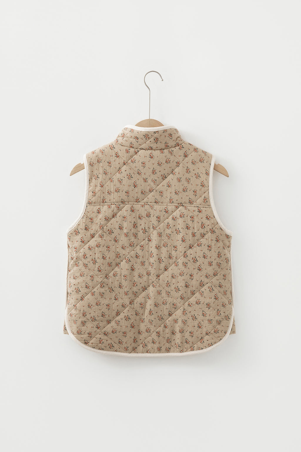 Veste matelassée beige à motif floral sur cintre, dos avec empiècements, sans manches