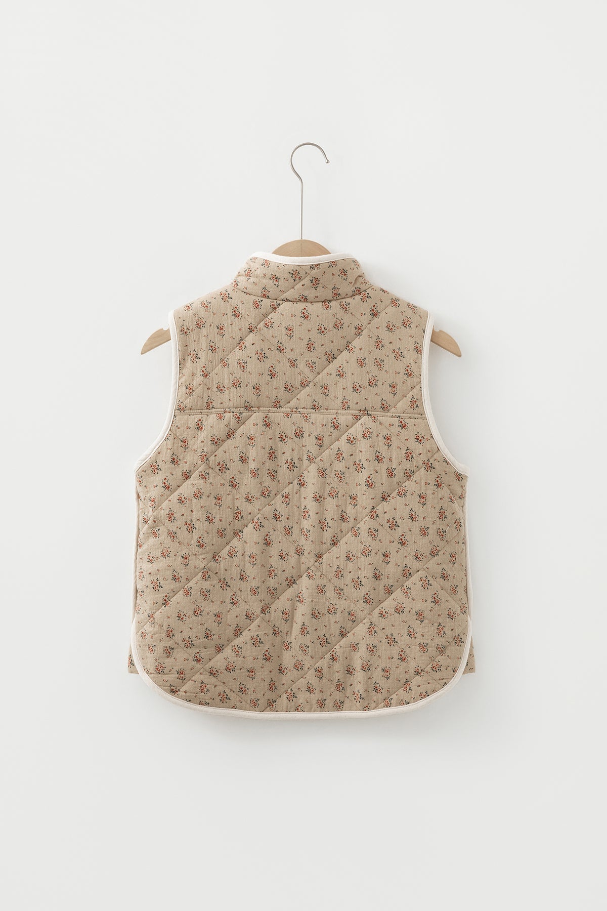 Veste matelassée beige à motif floral sur cintre, dos avec empiècements, sans manches