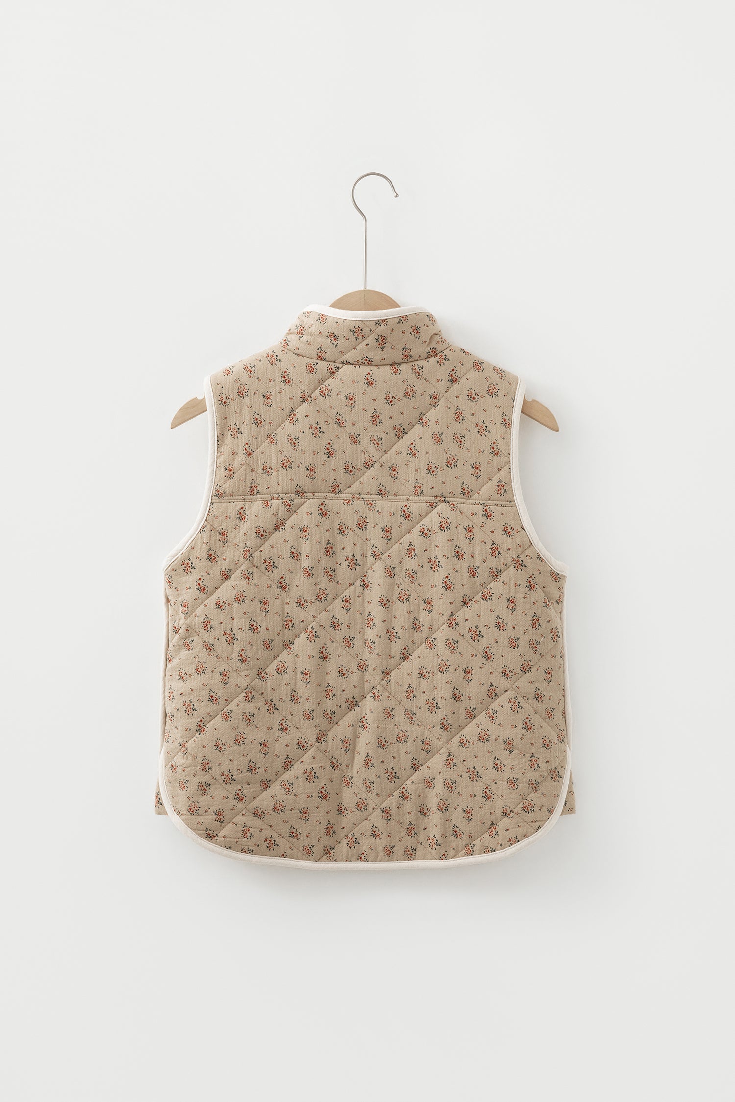 Veste matelassée beige à motif floral sur cintre, dos avec empiècements, sans manches
