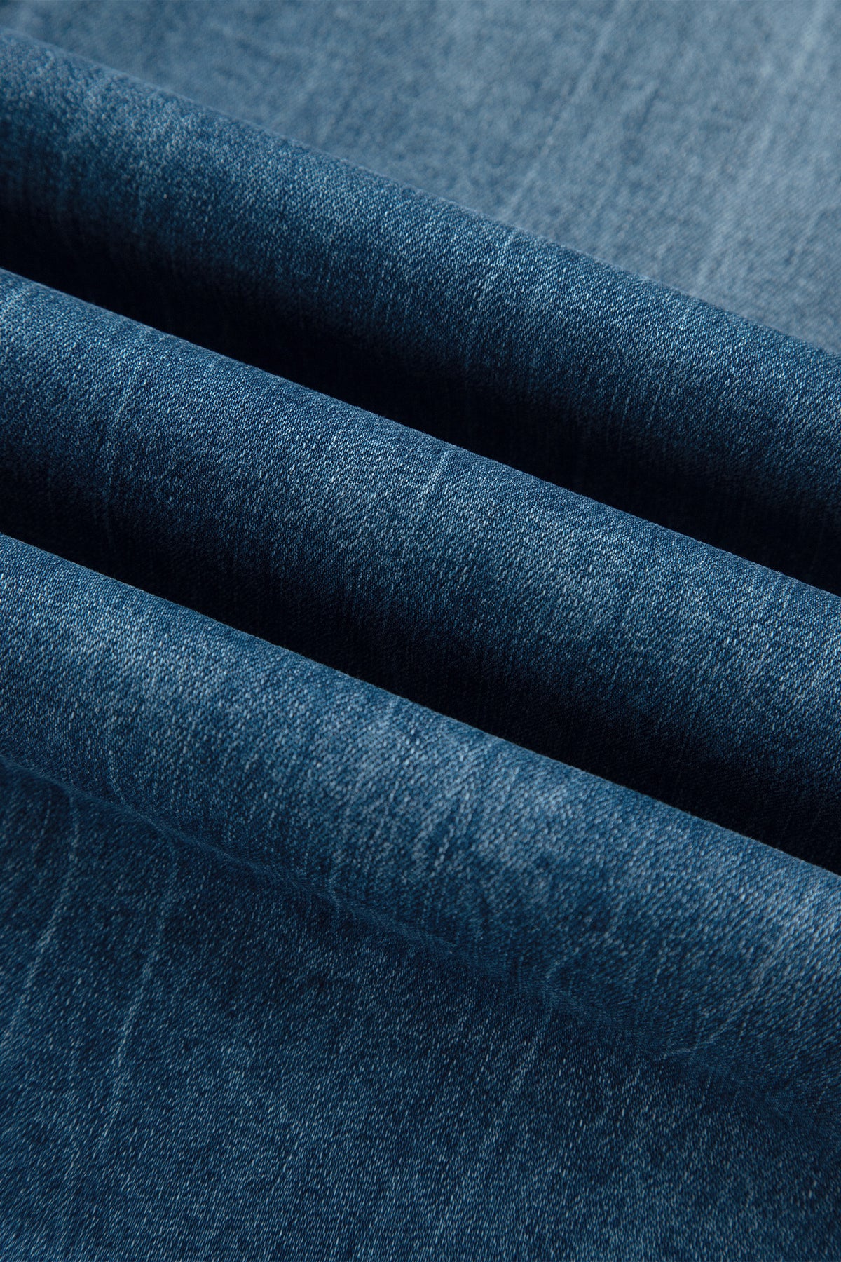 Détail tissu denim du jean flare bleu moyen, texture et coutures visibles.