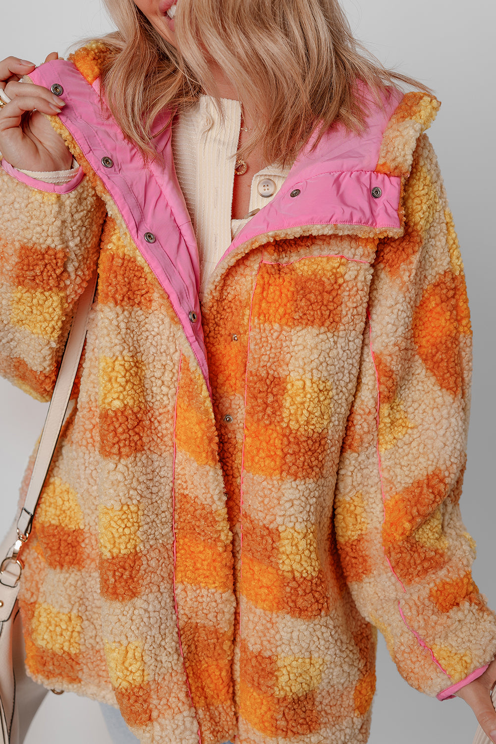 Veste sherpa orange à carreaux, capuche doublée rose, boutons pression visibles