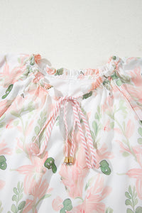 Robe courte rose à fleurs, encolure froncée avec nœud rayé au centre.