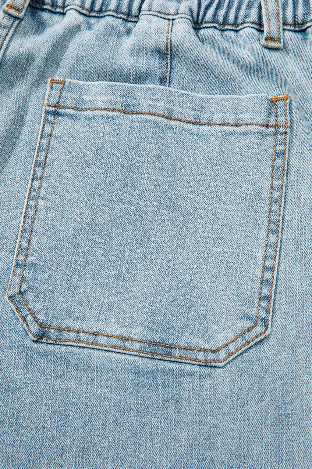 Jean bleu ciel : poche avant carrée avec surpiqûres et coutures orange.