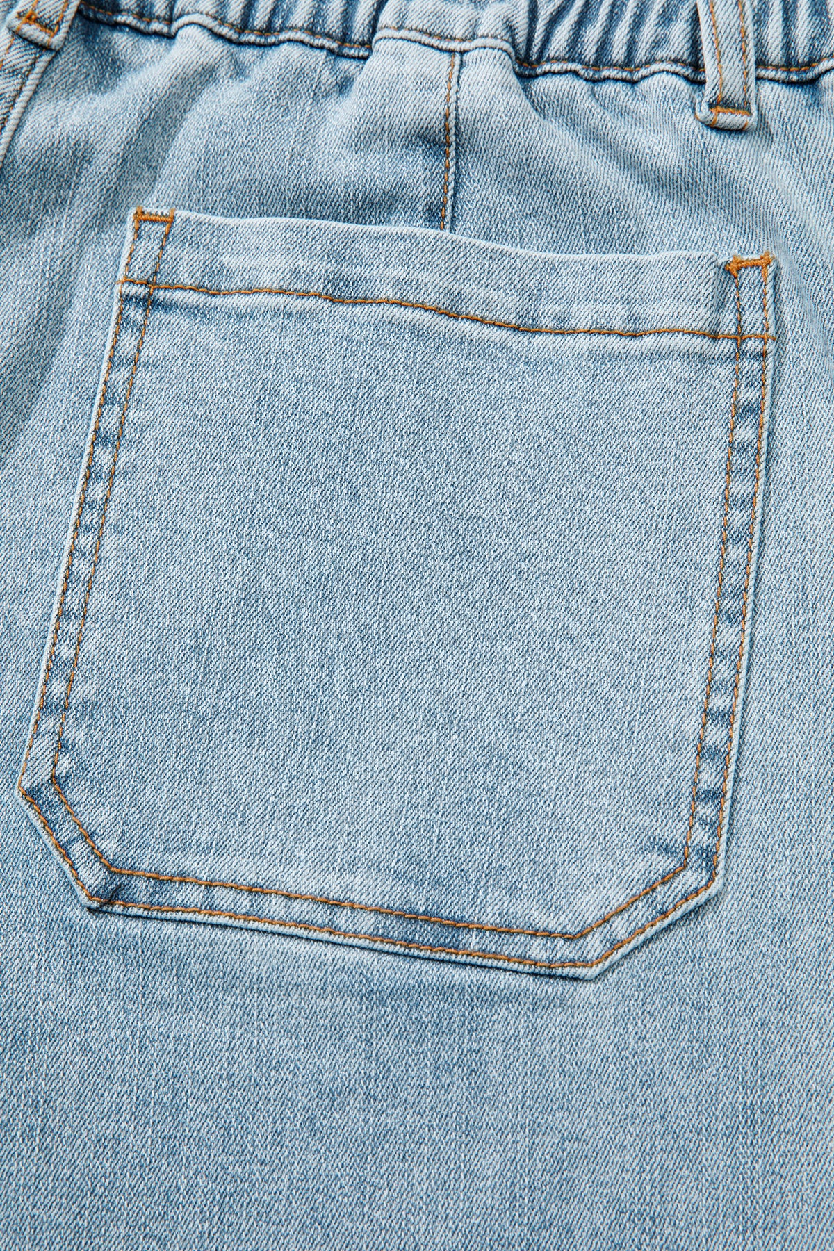 Jean bleu ciel : poche avant carrée avec surpiqûres et coutures orange.
