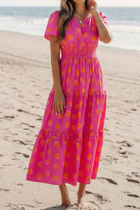 Robe mi-longue rose à pois, encolure V, manches courtes et volants superposés.