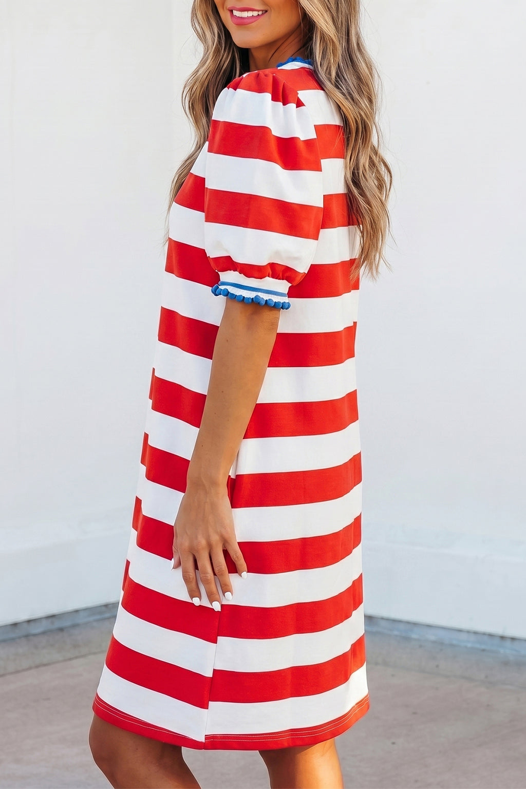 Robe mini à rayures rouges et blanches, manches bouffantes et bordure bleue.