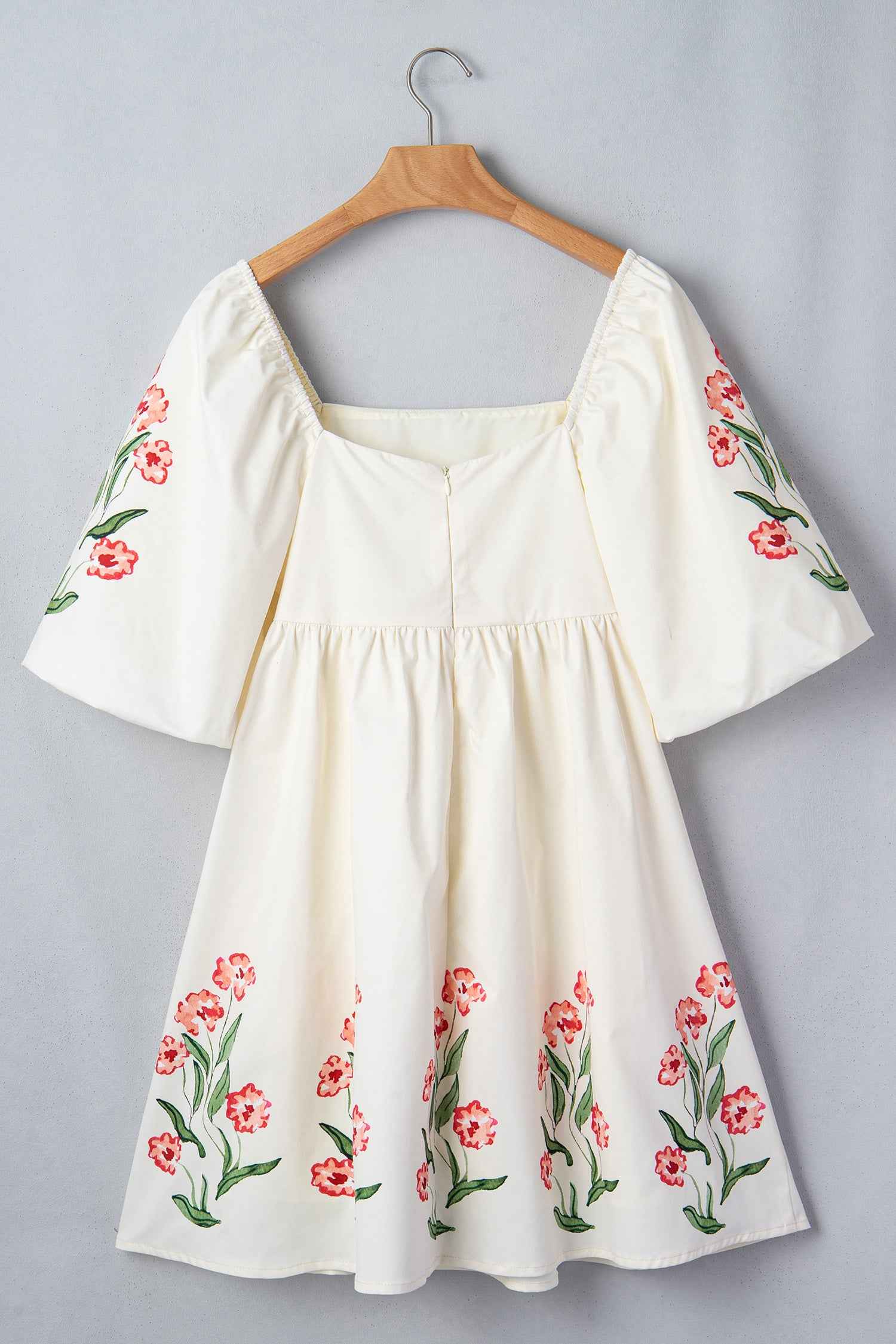 Robe babydoll crème avec manches bouffantes à fleurs rouges et encolure carrée.