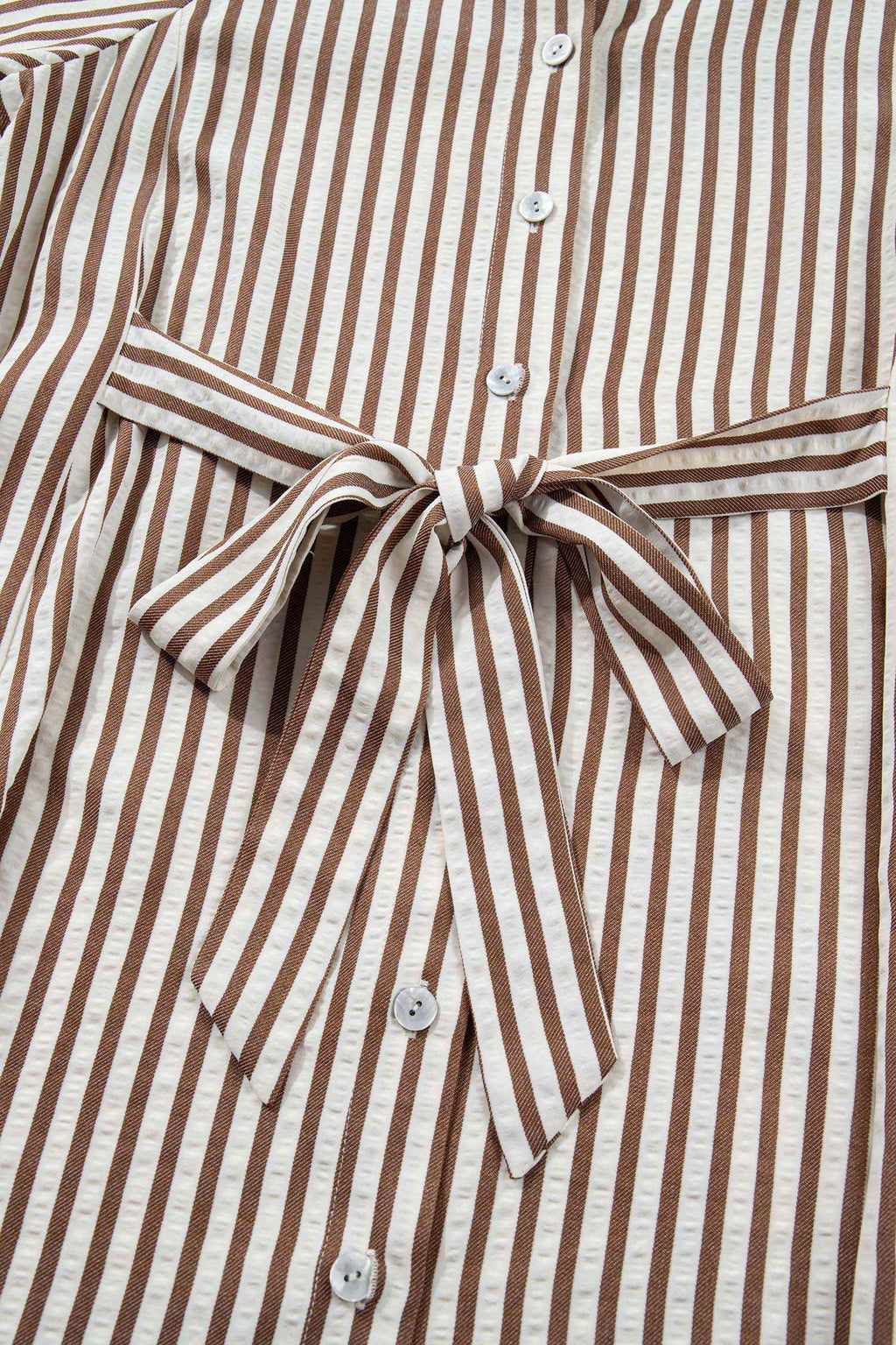 Détail robe: rayures brunes, nœud à la taille, boutons, col chemise.
