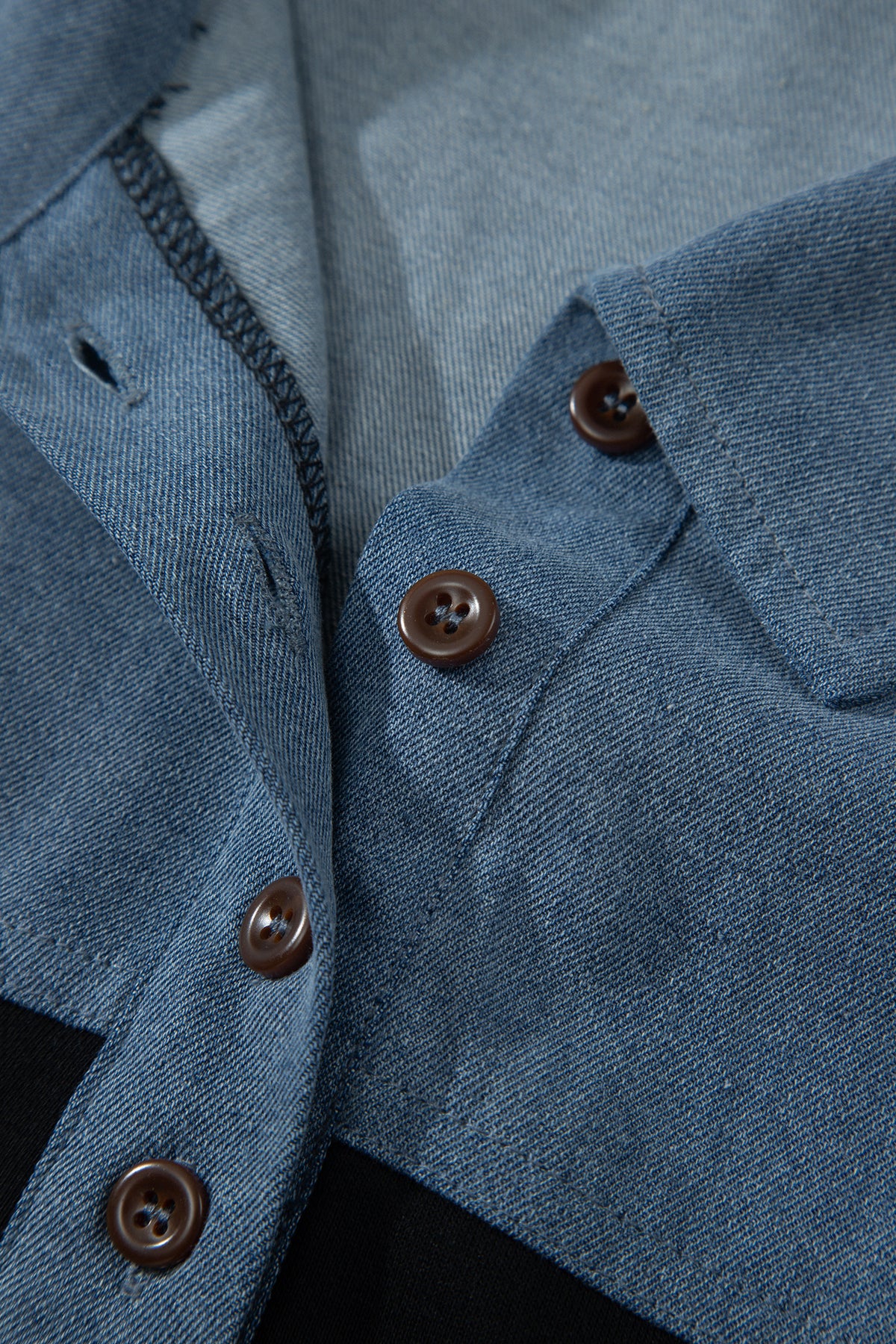 Haut polo bicolore en denim, gros plan patte boutonnée et col relevé.