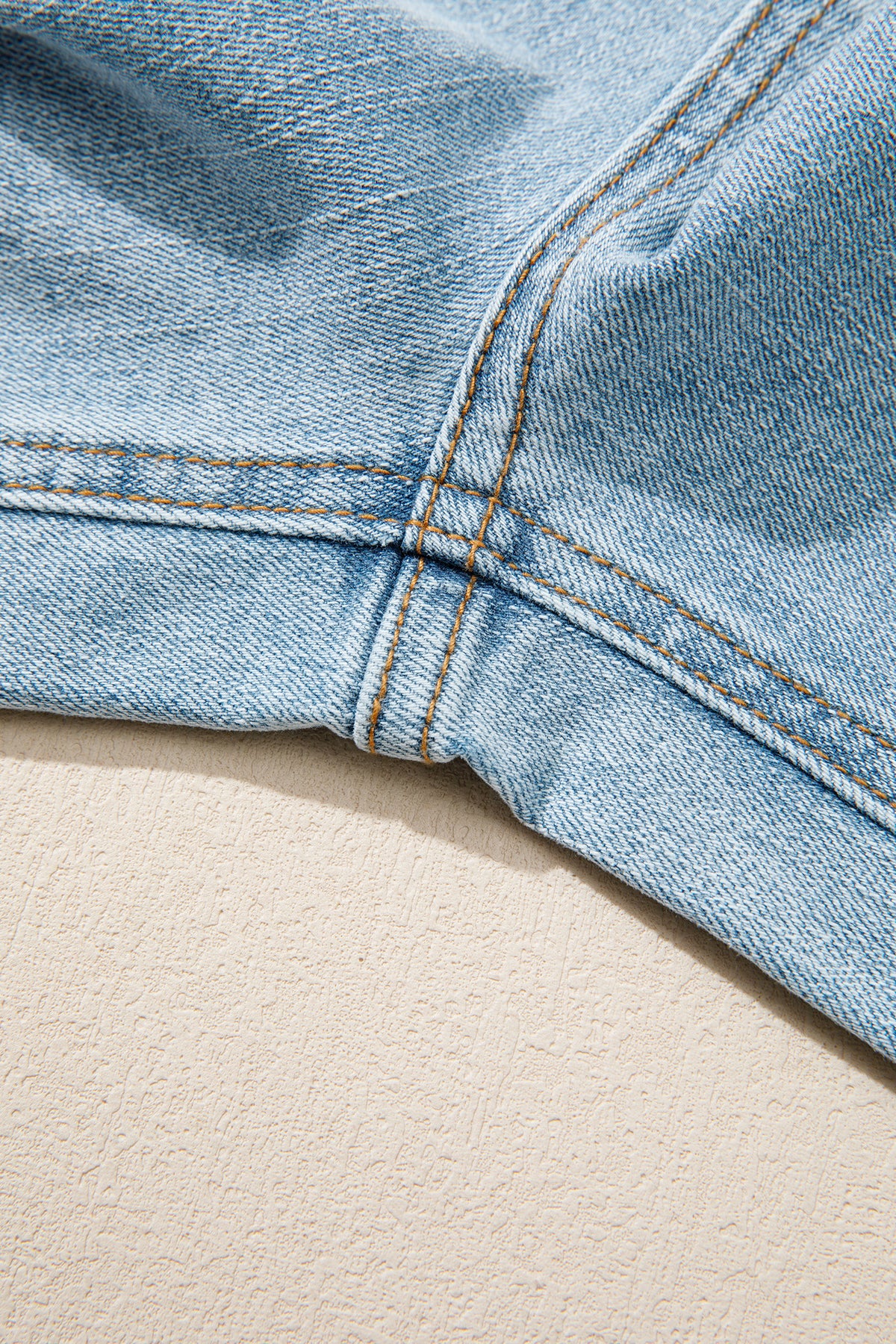 Jean bleu ciel : surpiqûres près de la couture d’entrejambe et texture du denim.