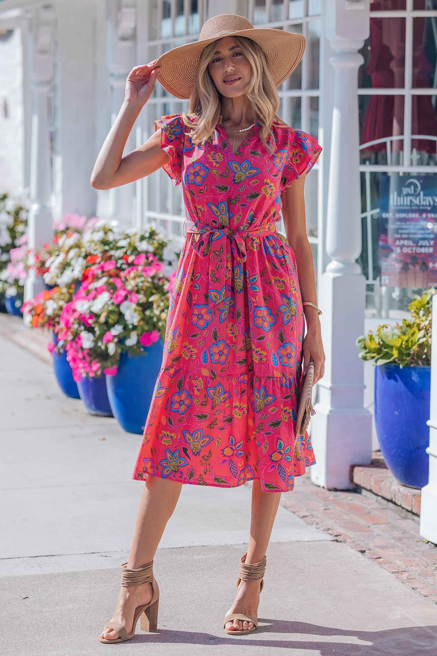 Robe longue fuchsia fleurie, ceinture à nouer, manches volantées, décolleté en V.
