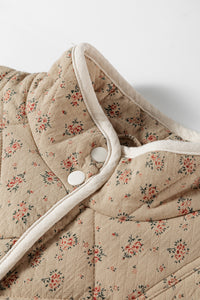 Veste matelassée beige à motif floral, col bordé de blanc et bouton pression visible