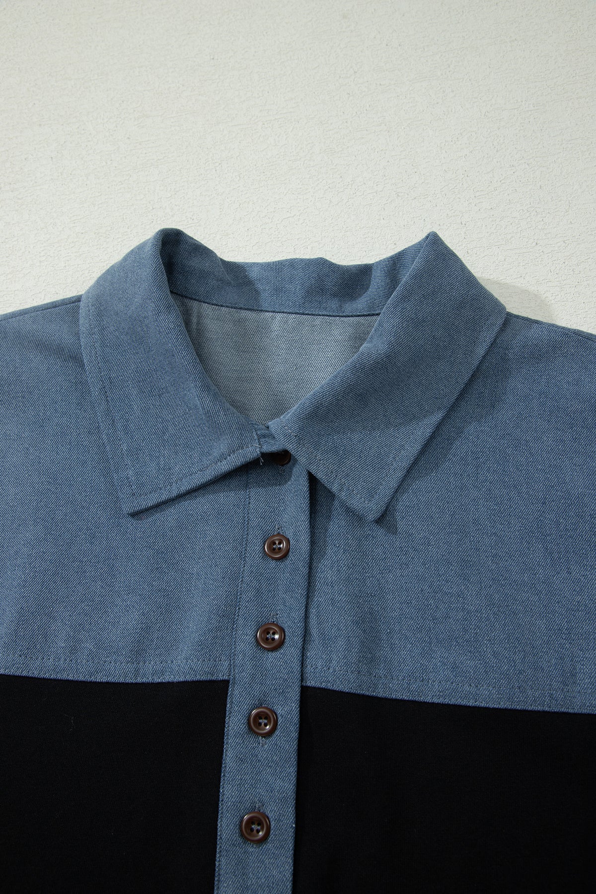 Haut polo bicolore en denim, col boutonné et rangée de boutons brun foncé.