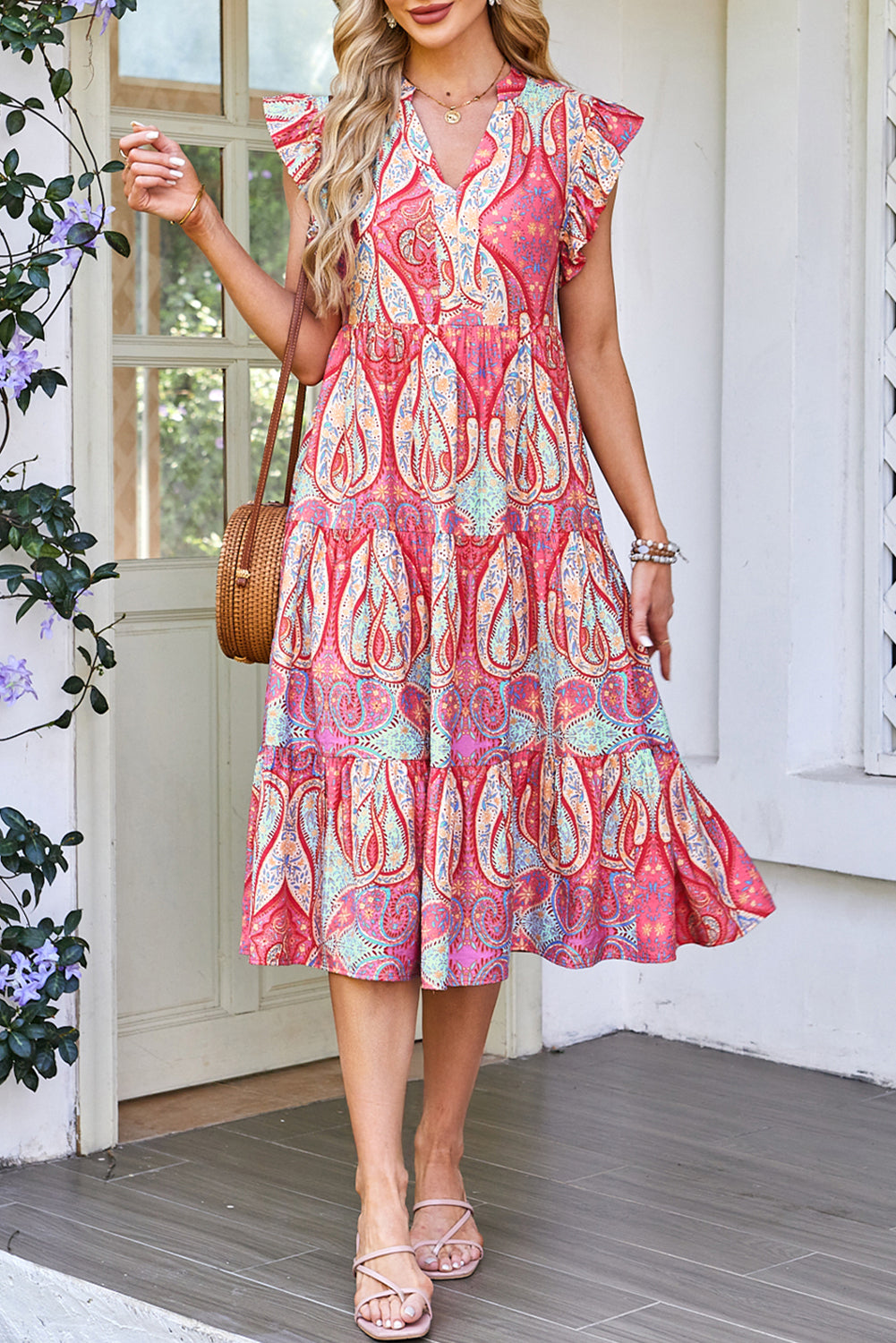 Robe mi-longue rose motif paisley, col en V, manches volantées, jupe à volants superposés.