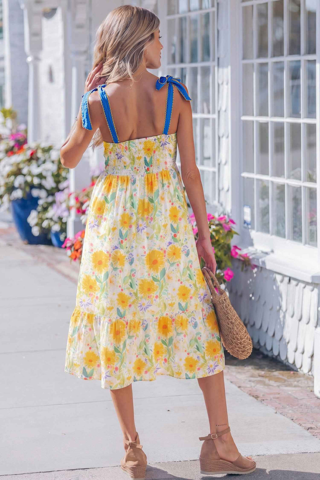Robe midi imprimée florale jaune vue de dos, bretelles à nœuds bleus et taille haute.
