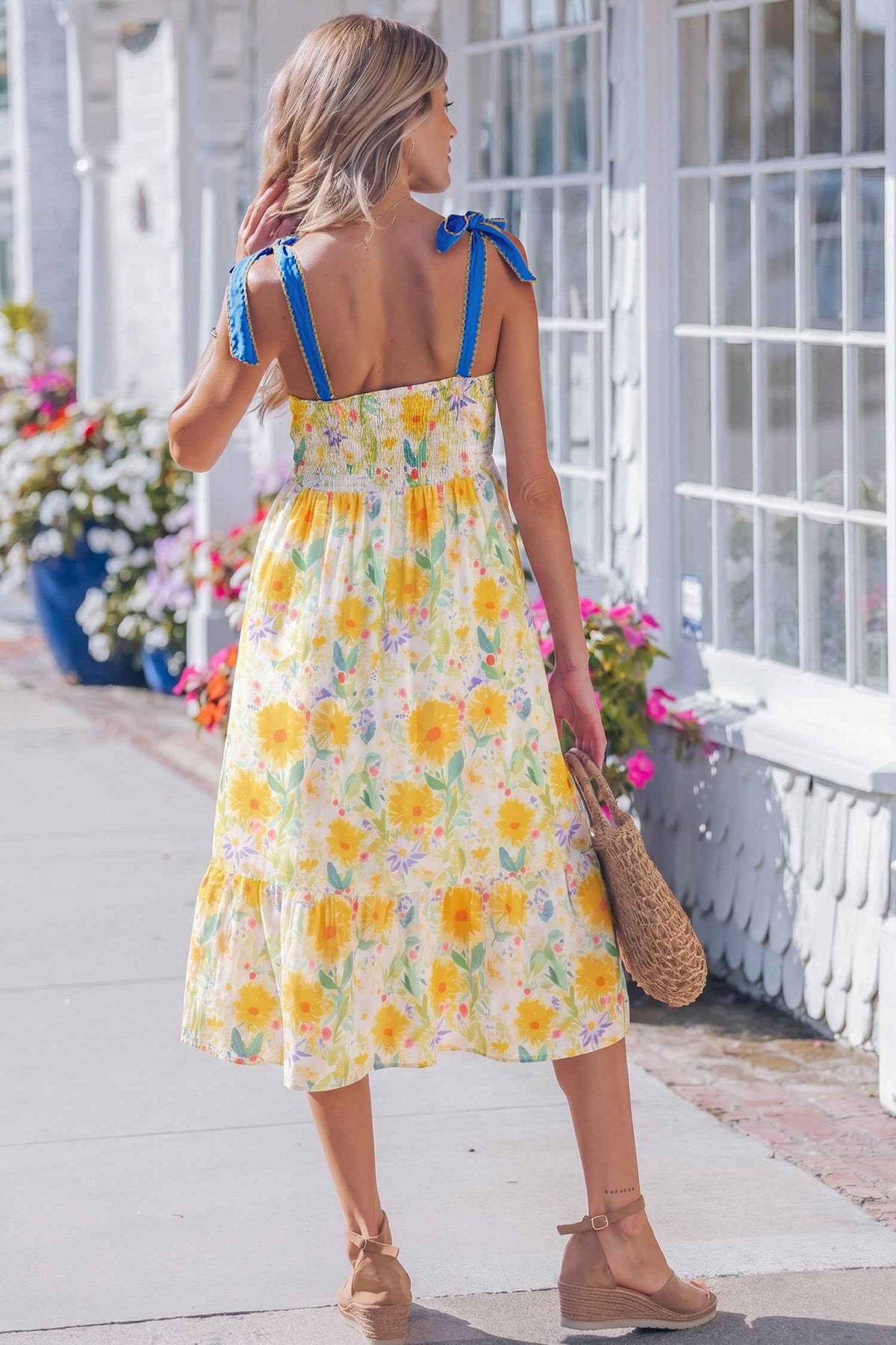 Robe midi imprimée florale jaune vue de dos, bretelles à nœuds bleus et taille haute.