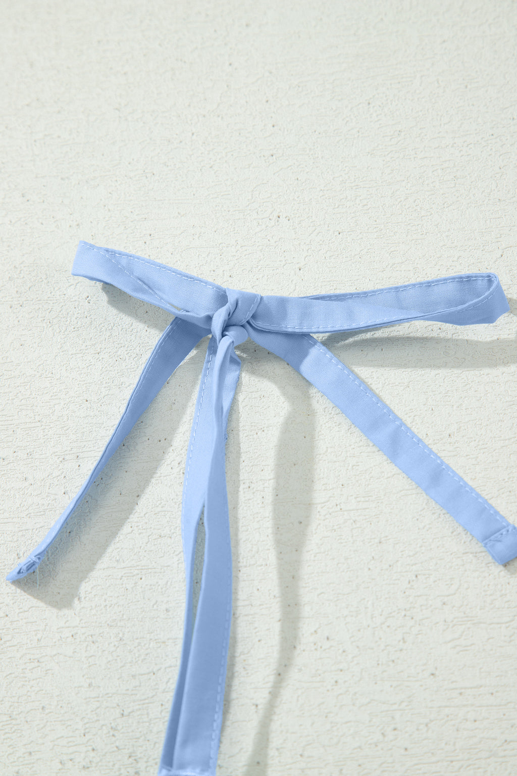Nœud de bretelles bleu clair sur robe, ruban noué, finition soignée.
