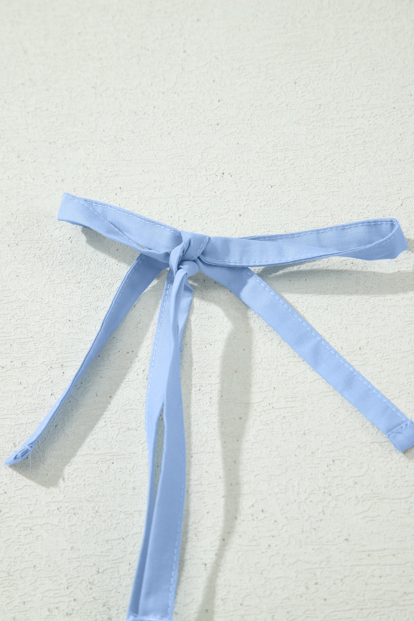 Nœud de bretelles bleu clair sur robe, ruban noué, finition soignée.