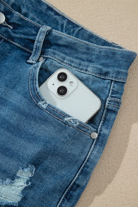 Détail poche jean taille haute bleu moyen, bouton, téléphone dans la poche.
