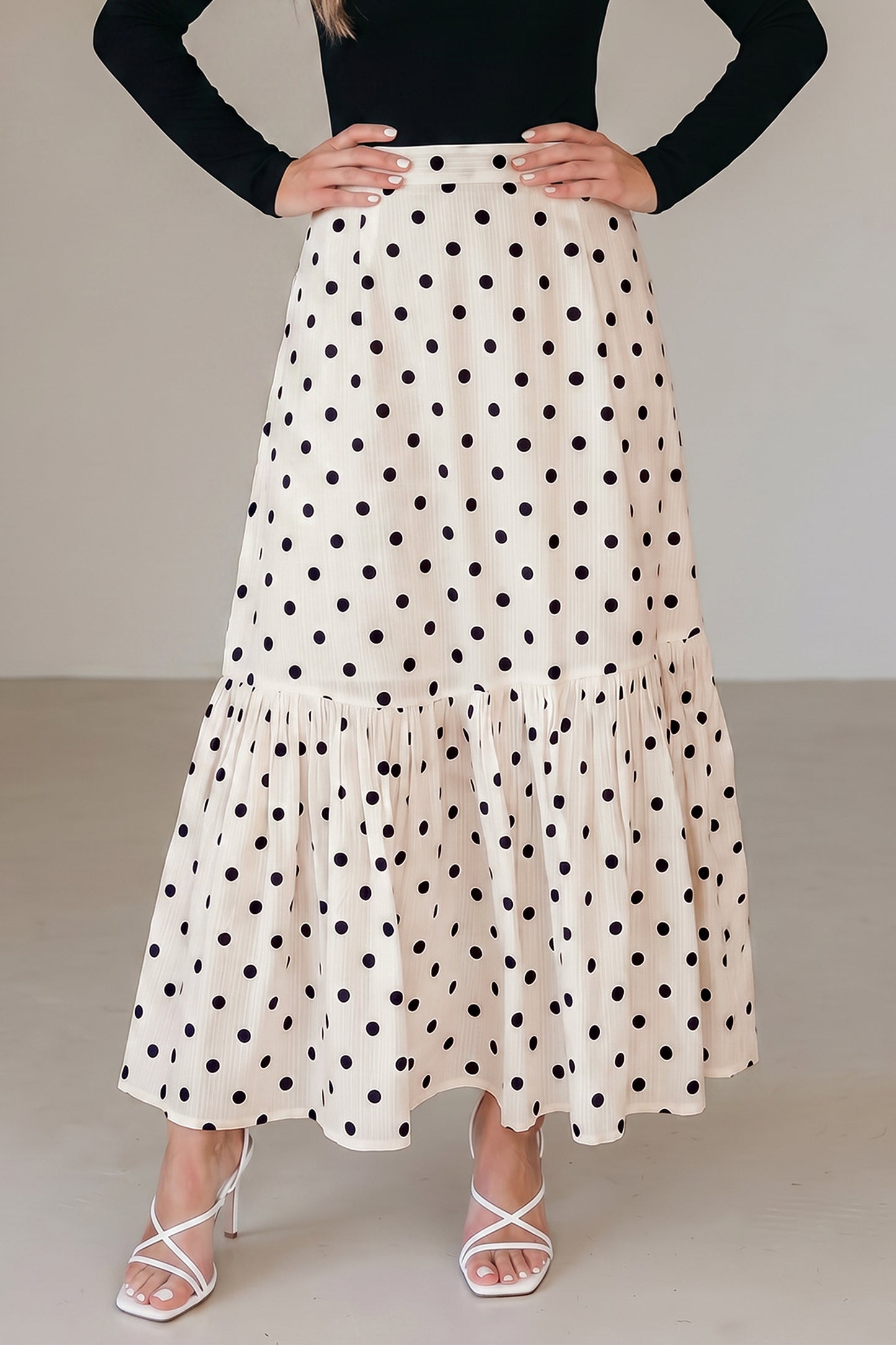 Jupe longue blanche à pois noirs, volants en bas et taille élastique.