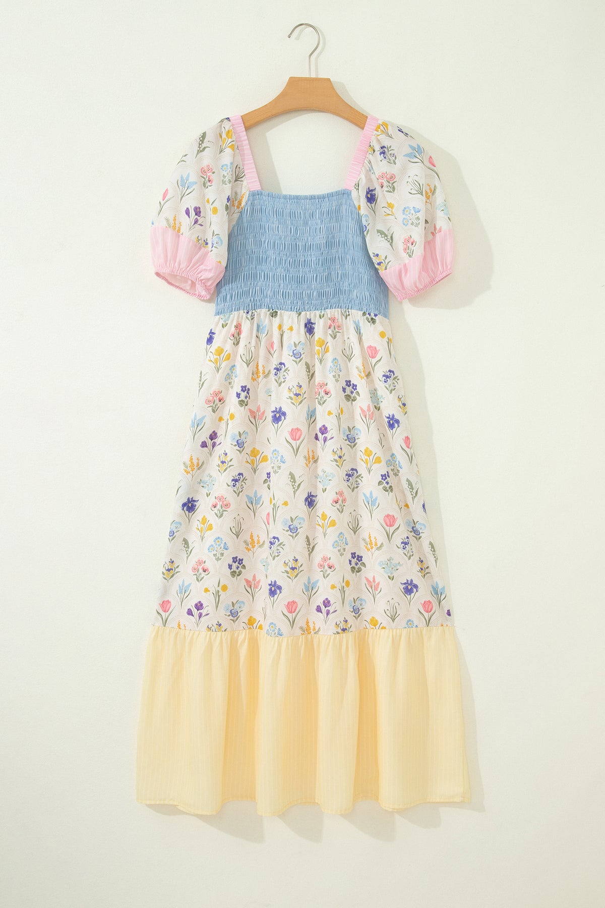 Robe longue sur cintre: buste bleu smocké, jupe fleurie, volant bas crème, manches bouffantes roses.
