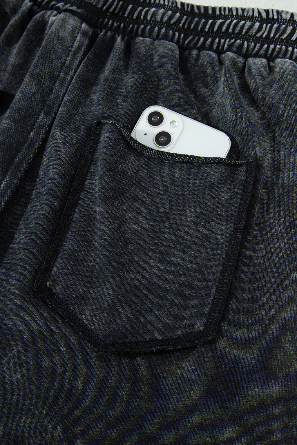 Détail pantalon noir délavé minéral : poche plaquée, taille élastique, cordon de serrage