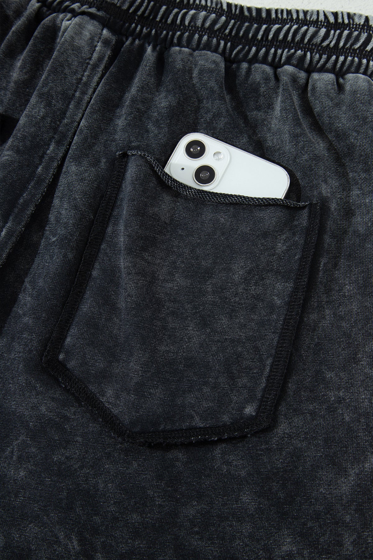 Détail pantalon noir délavé minéral : poche plaquée, taille élastique, cordon de serrage