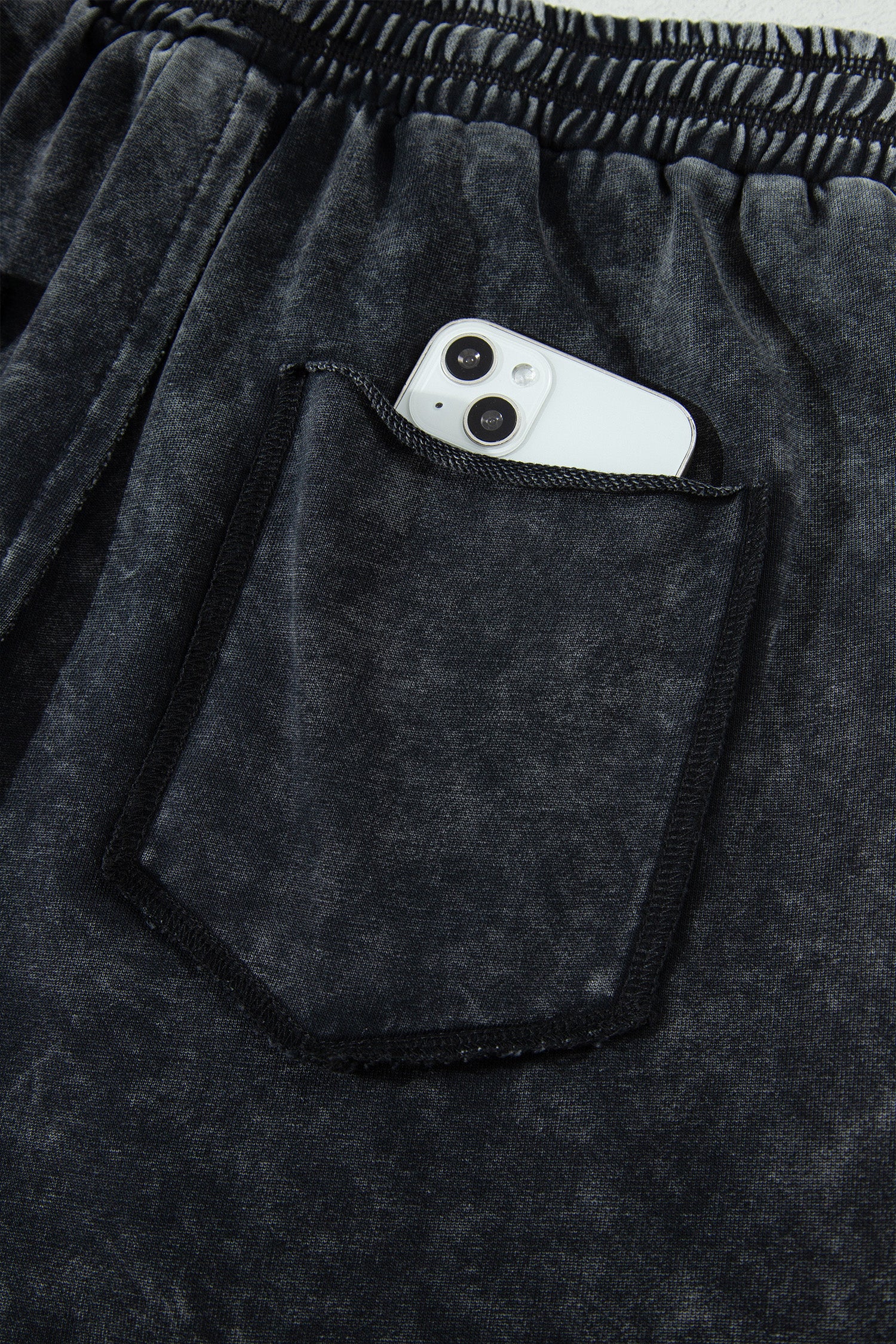 Détail pantalon noir délavé minéral : poche plaquée, taille élastique, cordon de serrage