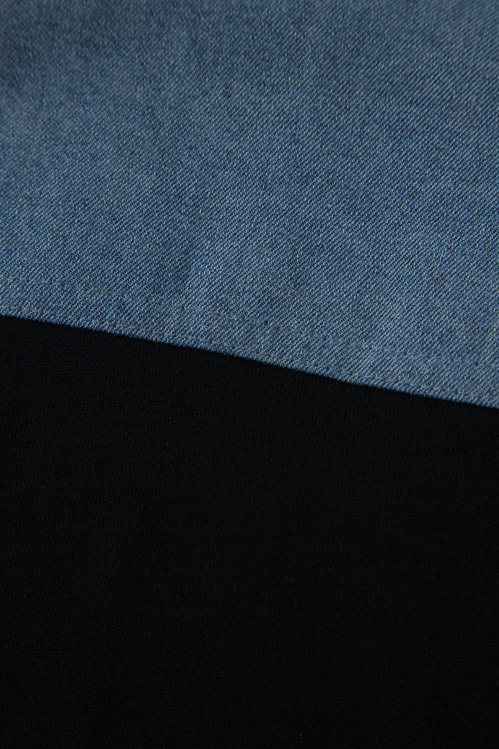 Haut polo bicolore en denim, empiècement supérieur bleu et base noire.