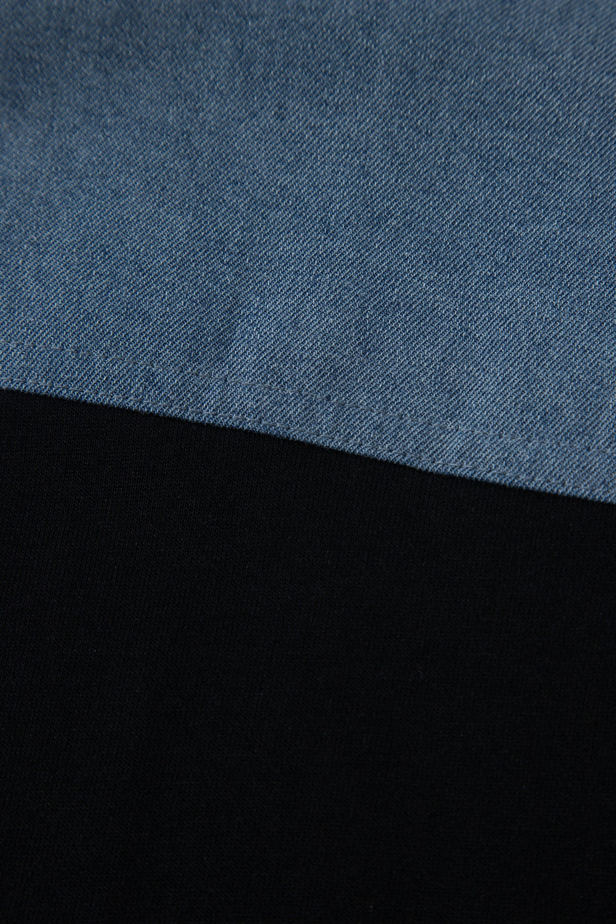 Haut polo bicolore en denim, empiècement supérieur bleu et base noire.