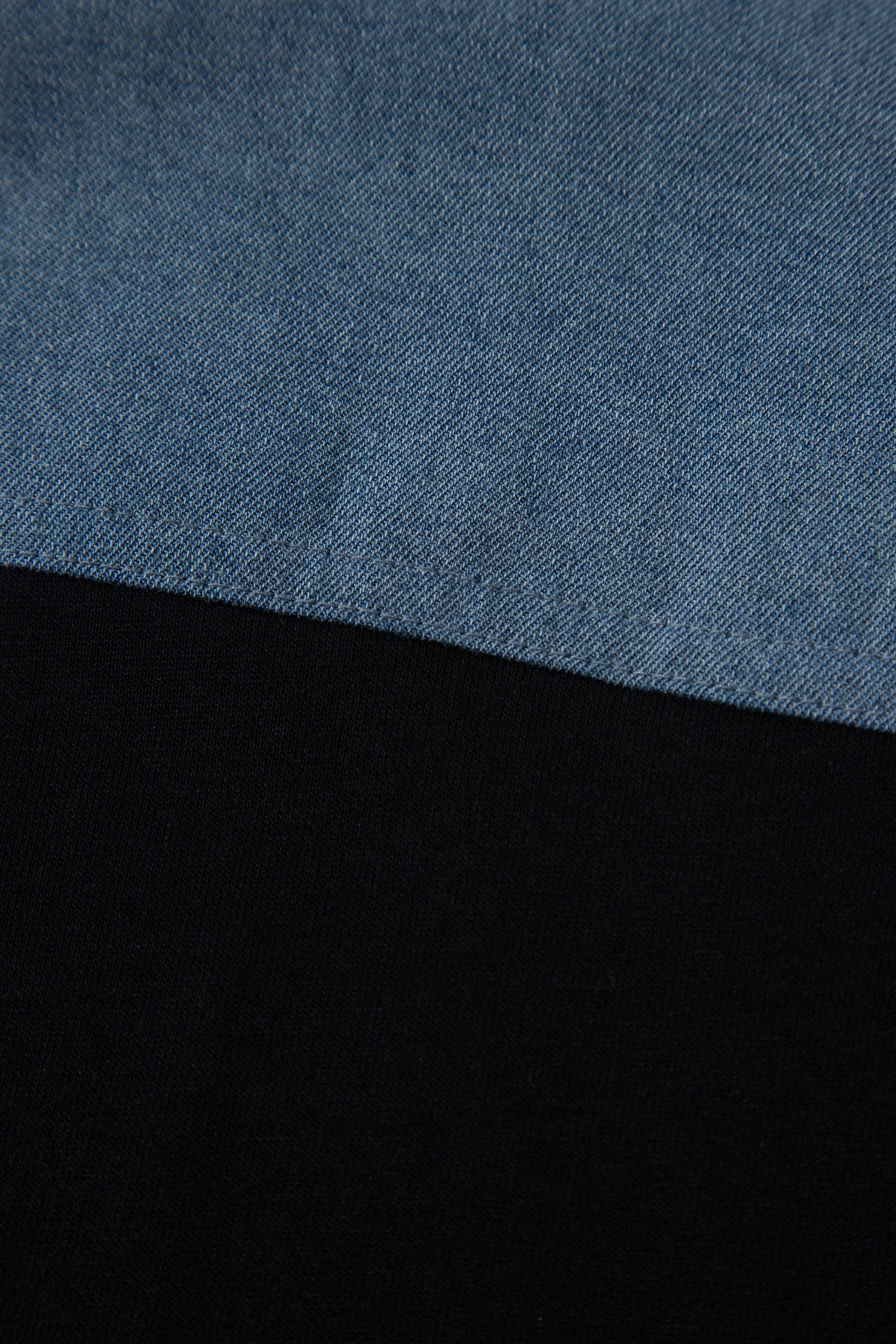 Haut polo bicolore en denim, empiècement supérieur bleu et base noire.