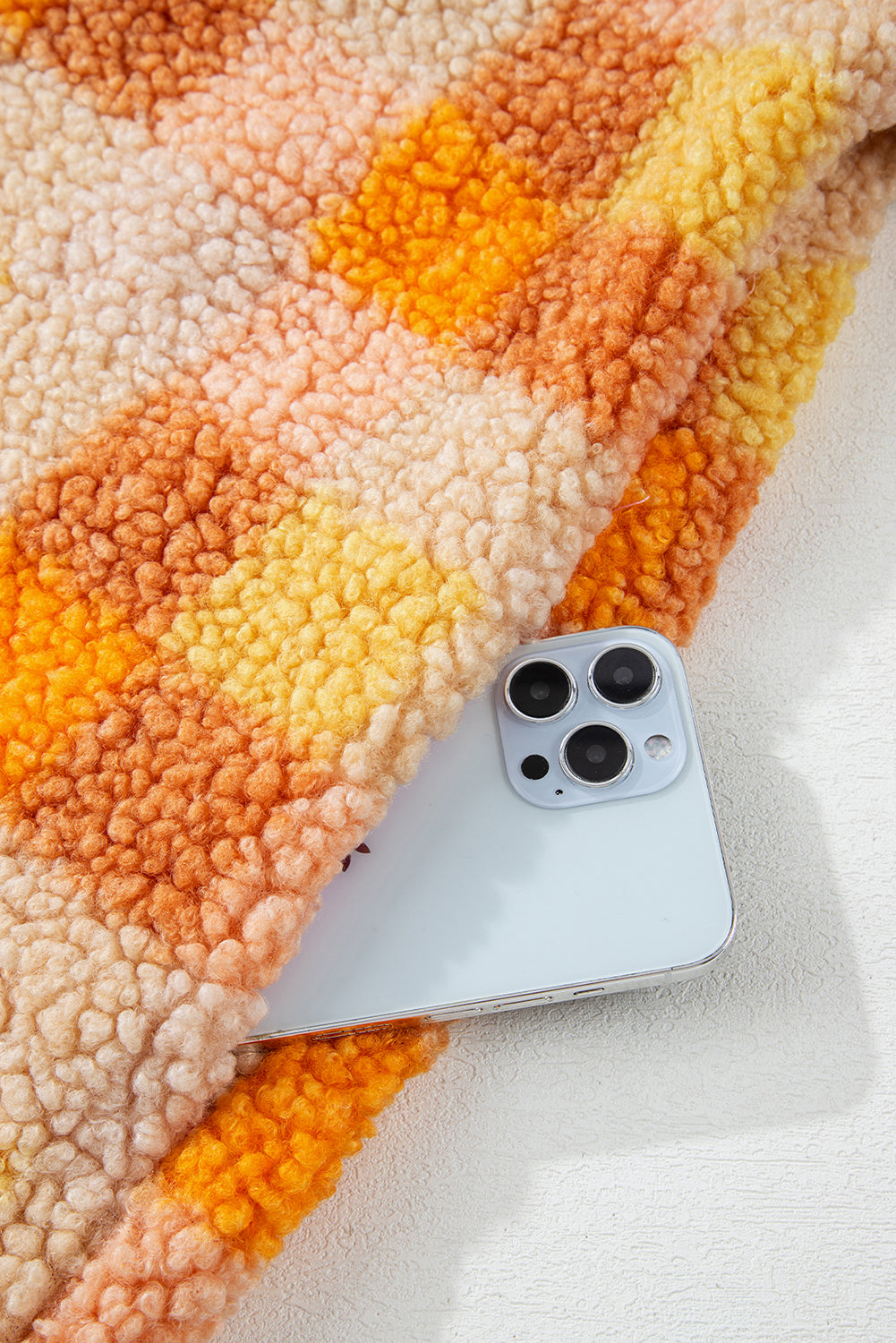 Tissu sherpa orange à carreaux avec doublure rose; téléphone posé