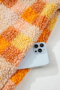 Tissu sherpa orange à carreaux avec doublure rose; téléphone posé