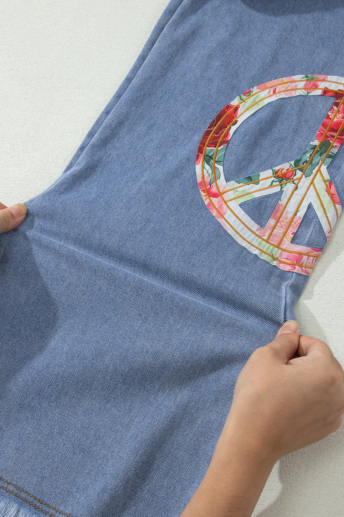 Jean bleu clair, patch floral signe de la paix sur la jambe