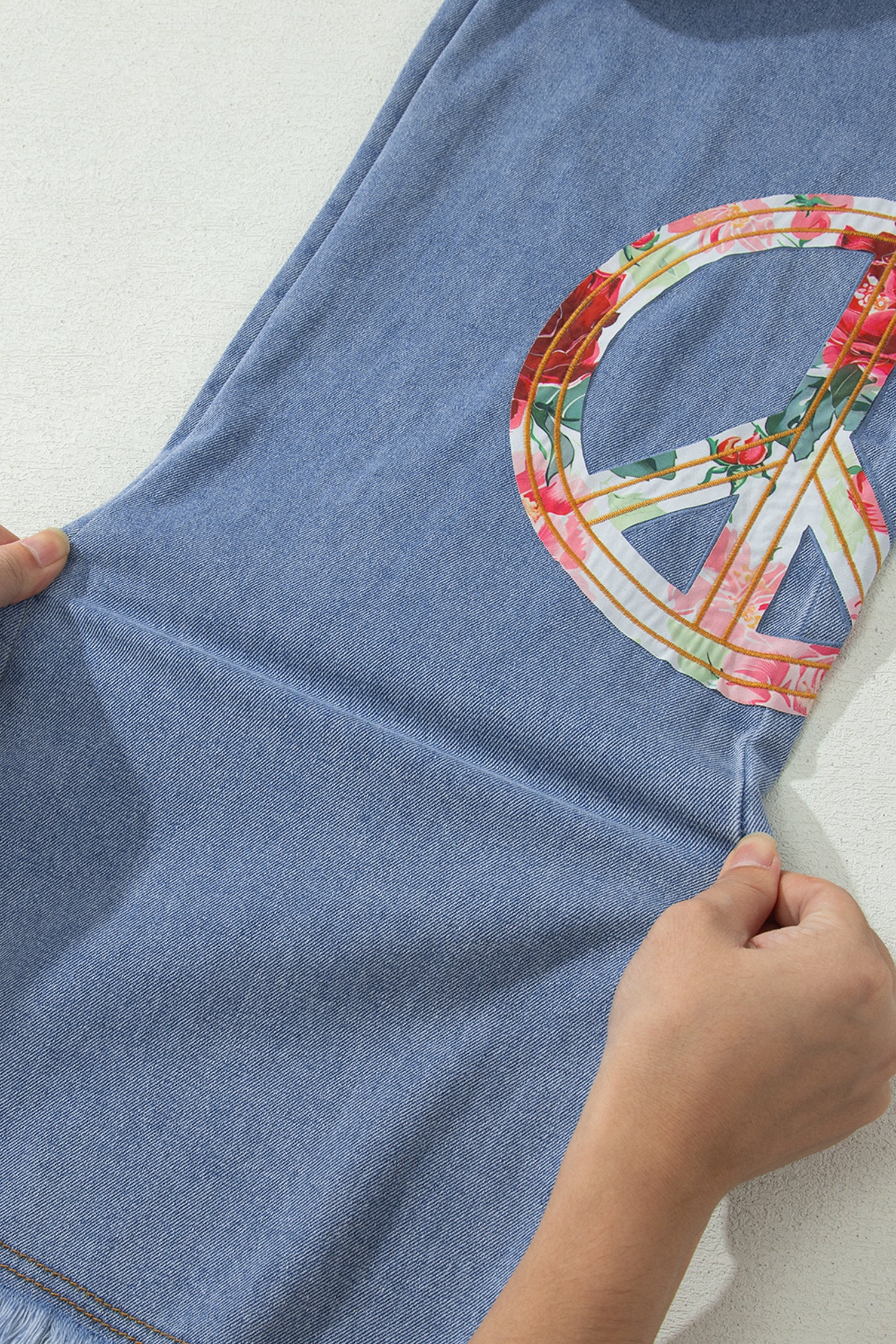 Jean bleu clair, patch floral signe de la paix sur la jambe