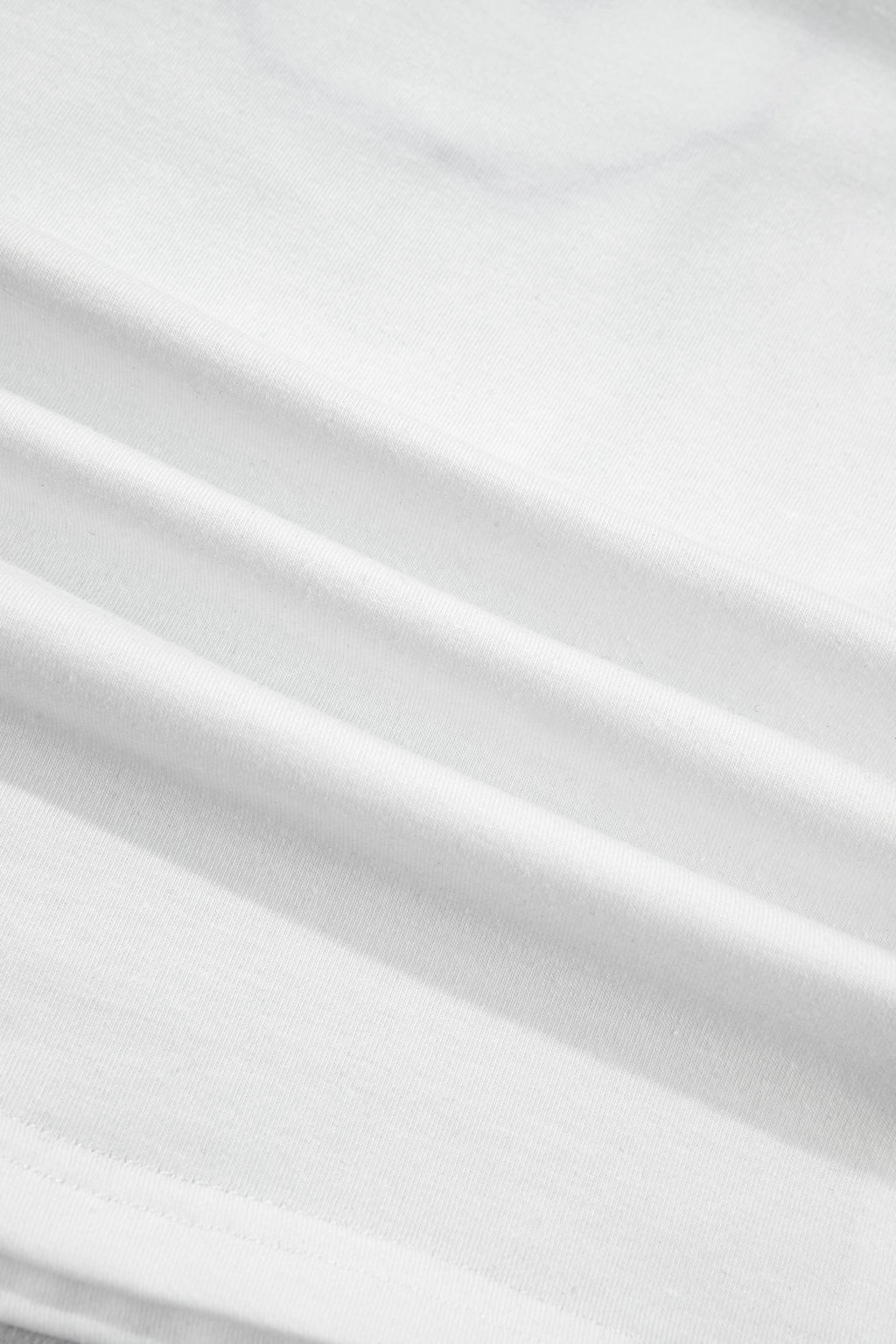 Tissu blanc du t-shirt, texture et plis visibles.