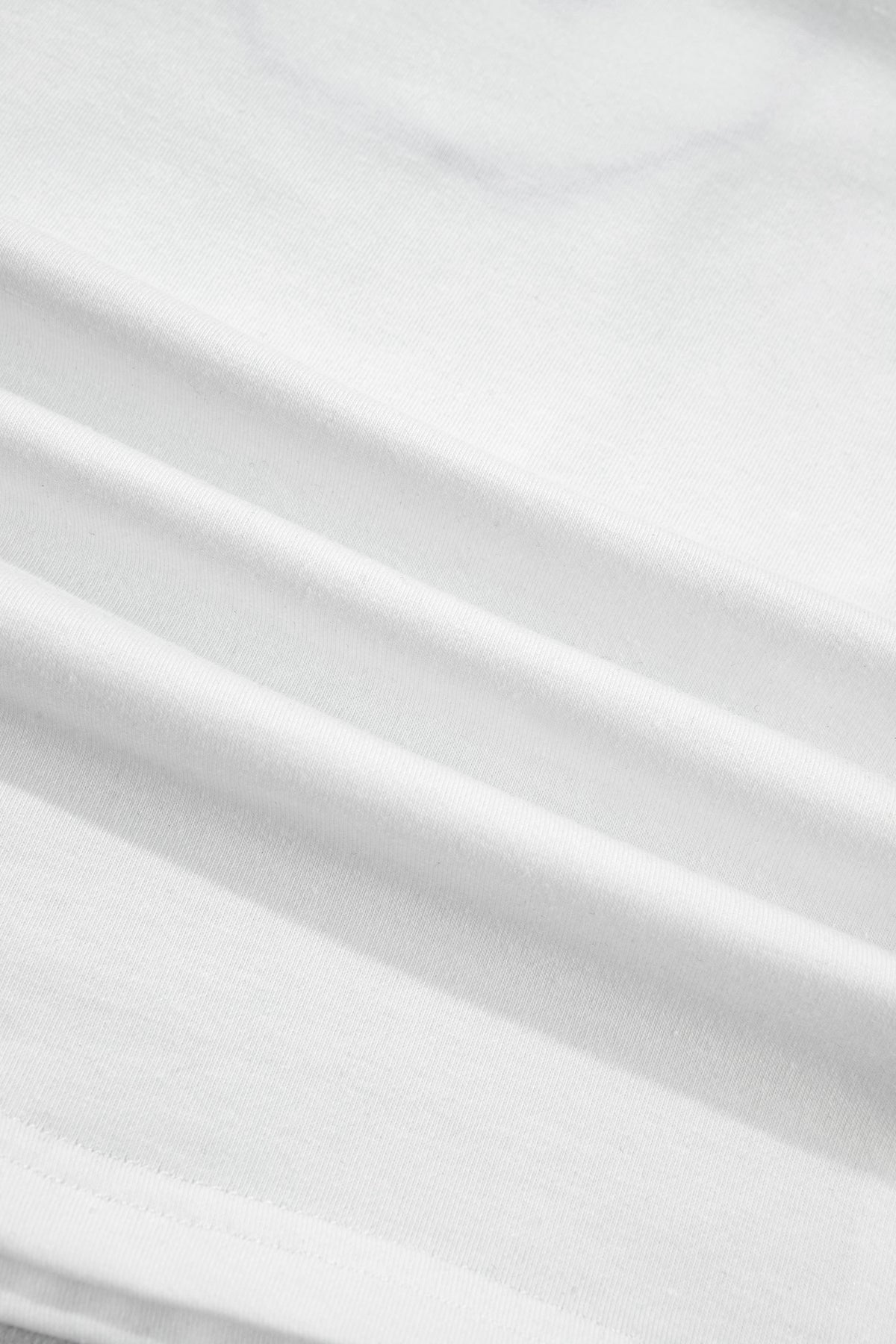 Tissu blanc du t-shirt, texture et plis visibles.