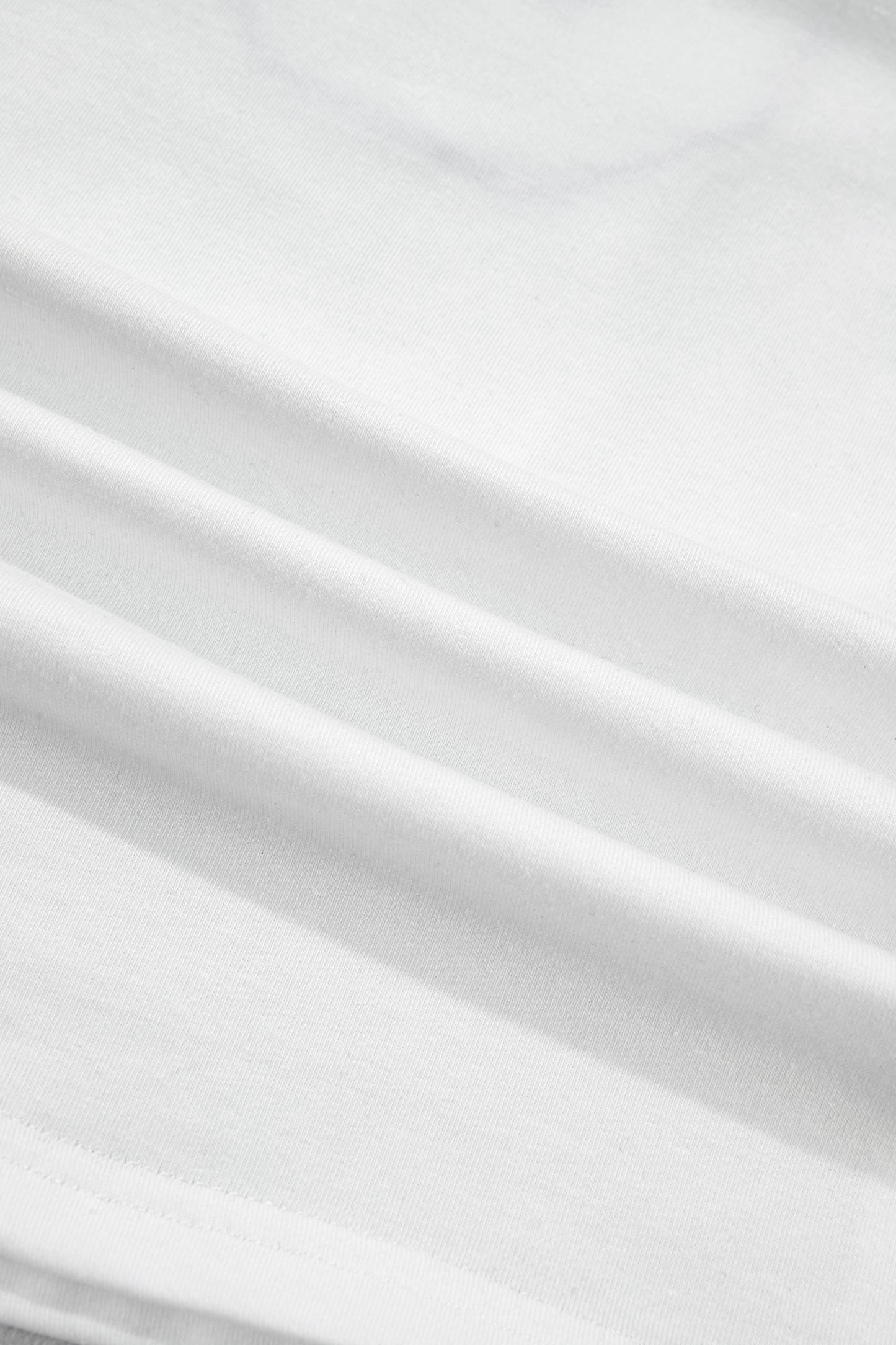 Tissu blanc du t-shirt, texture et plis visibles.